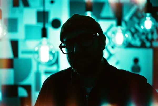 Silhouette of a bearded man backlit with cyan light